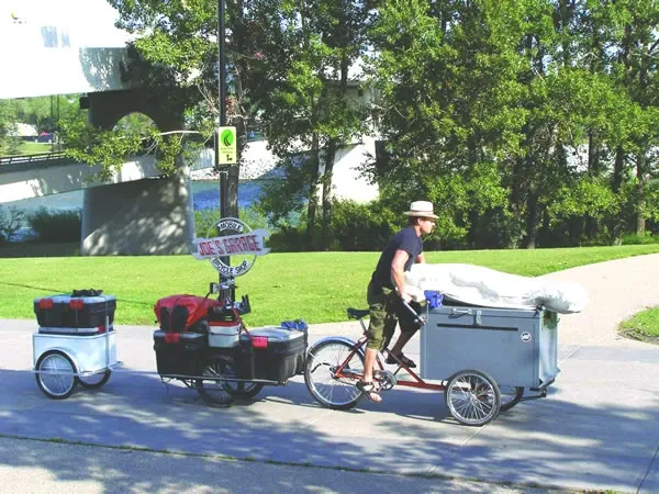 Joe transporting his entire mobile bike shop by cargo tricycle and trailer on the Bow River pathway