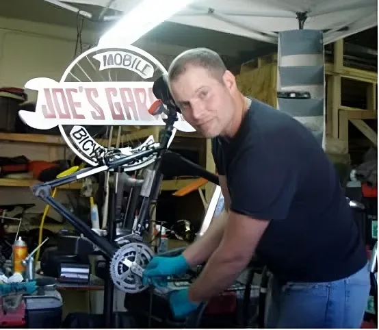 Joe working on a bike repair under the original Mobile Bicycle Shop sign